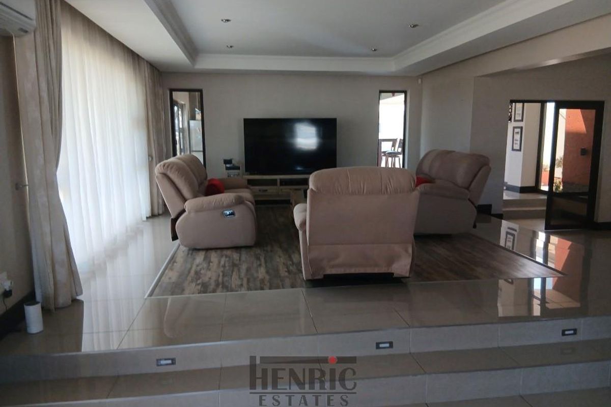 Spacious sunken living room featuring tiled flooring, recessed ceiling with downlights, and integrated step lighting, creating a modern and comfortable atmosphere.