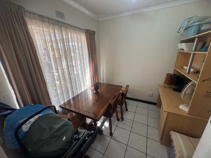 A functional dining area featuring tiled flooring and a large sliding glass door providing natural light.