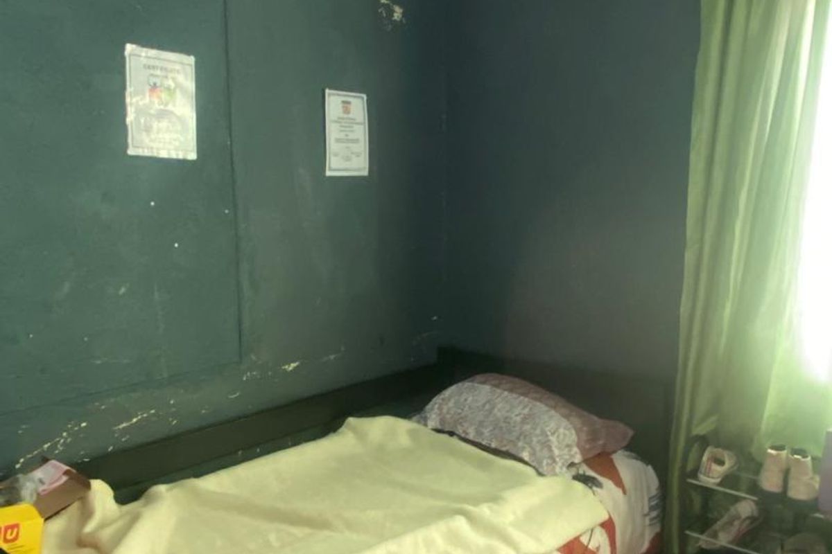 A bedroom featuring dark painted walls with visible surface wear and peeling paint, requiring cosmetic attention and refurbishment.