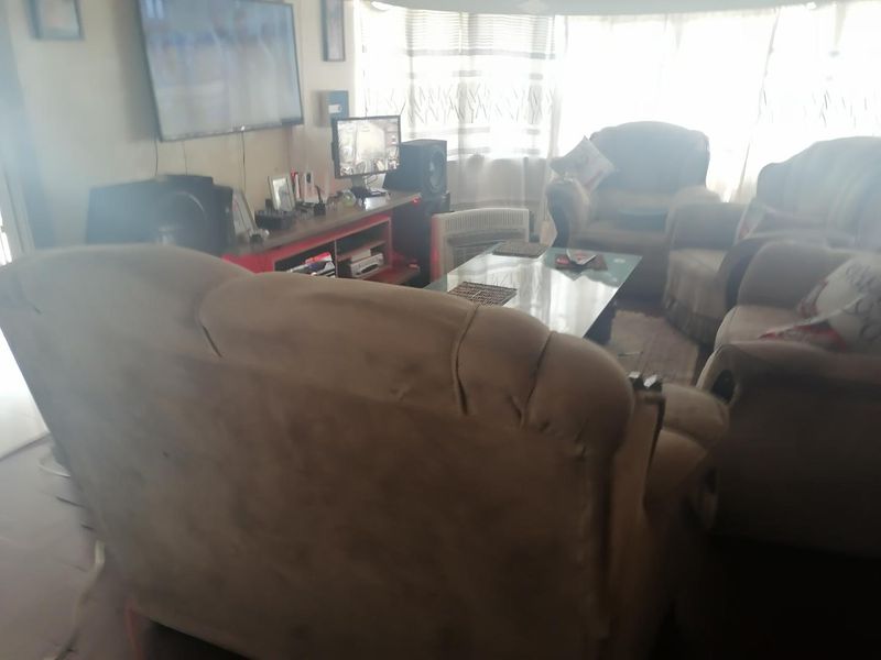 A living room area featuring large windows allowing natural light, providing a functional space for relaxation and entertainment.