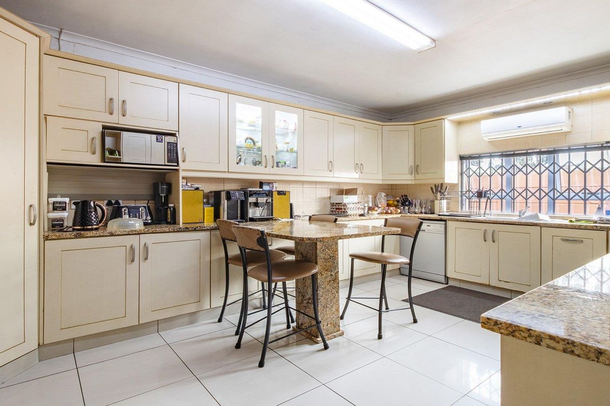 A functional kitchen featuring cream cabinetry, granite countertops, tiled flooring, and a built-in breakfast nook, providing ample storage and workspace.