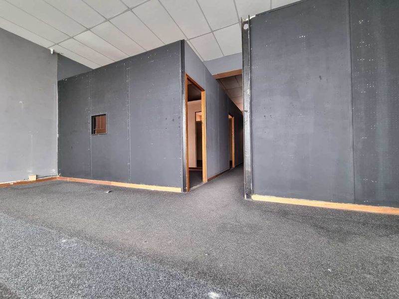 An empty office space featuring dark partition walls, suspended ceiling tiles, and carpet flooring, offering a blank canvas for commercial fit-out.