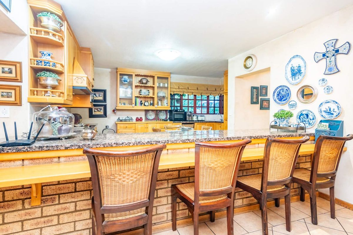 A traditional kitchen featuring light wood cabinetry, granite countertops, and a breakfast bar with a brick base, offering a warm and functional cooking space.