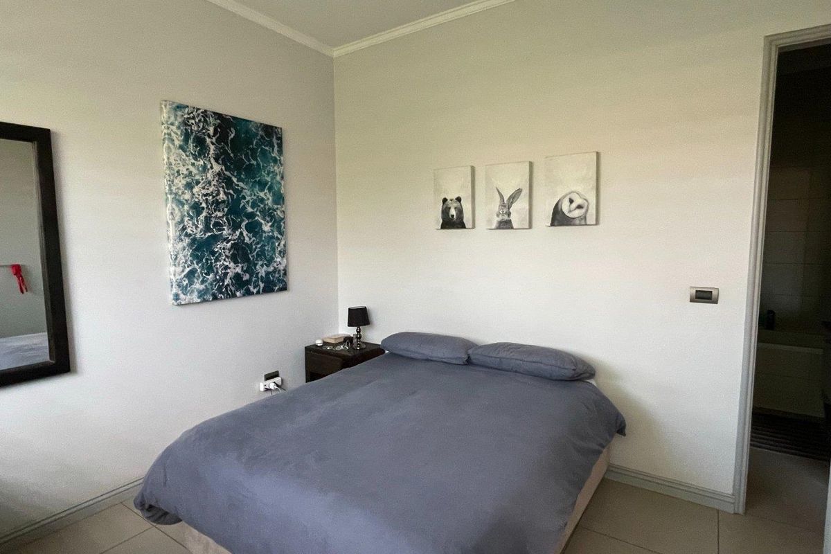 A well-maintained bedroom featuring neutral wall finishes, tiled flooring, and an adjoining bathroom entrance.