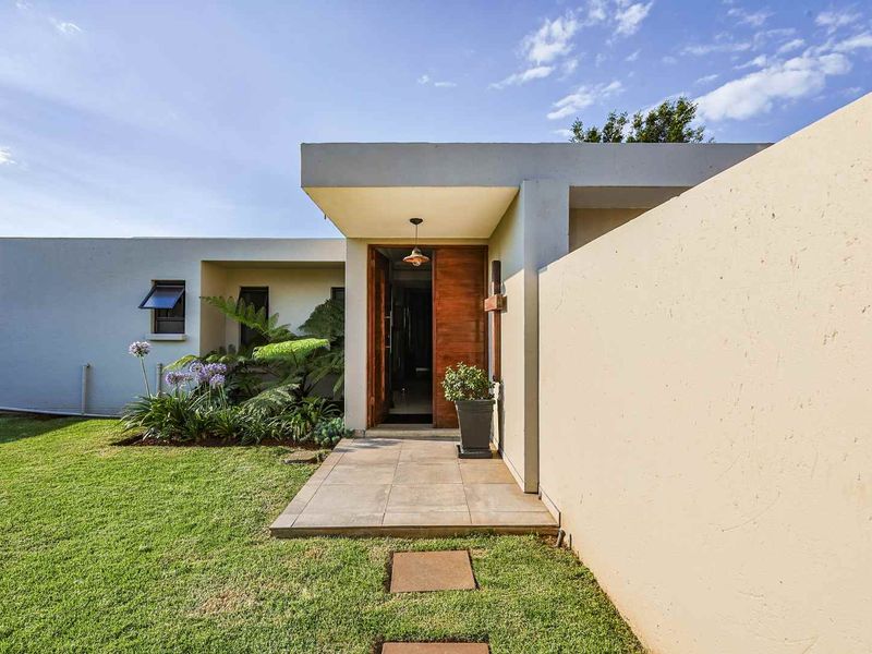 Modern front entrance featuring a solid timber door, tiled walkway, and clean architectural lines with a well-maintained garden.