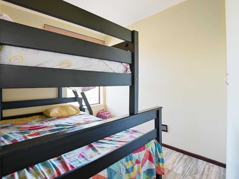 A functional bedroom featuring tiled flooring, a built-in wardrobe, and natural light from the window.