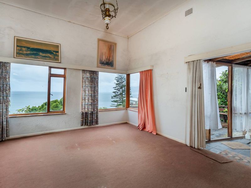 Spacious living area featuring large windows with ocean views, carpet flooring, and direct access to an outdoor patio area.