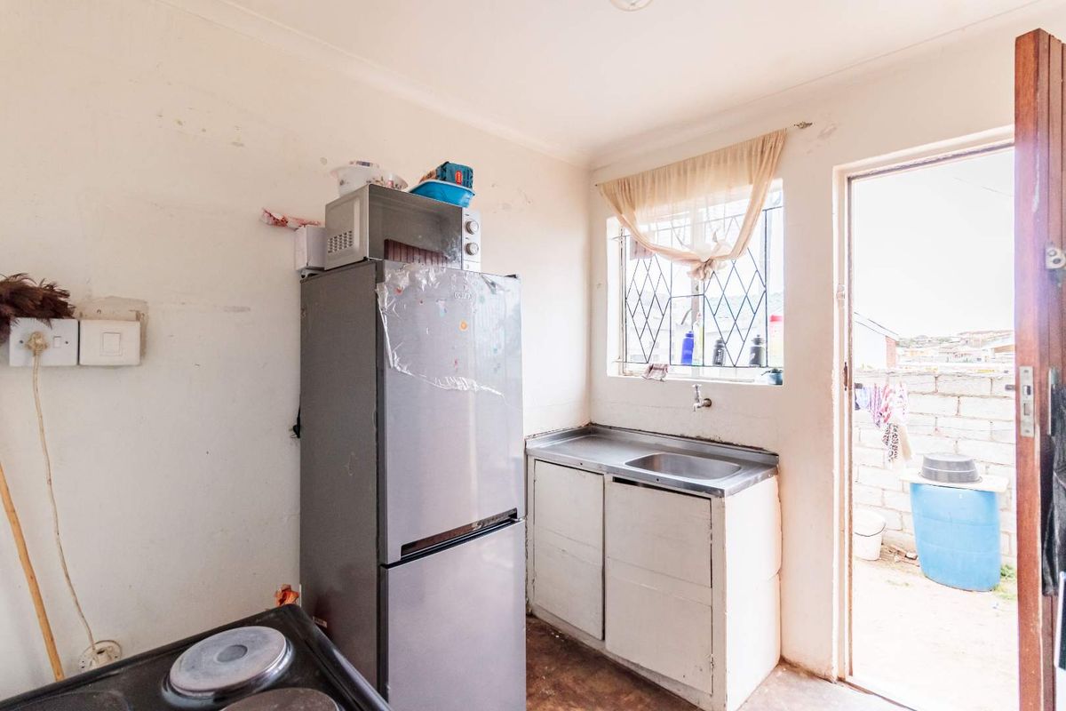 A compact kitchen area featuring a stainless steel sink, built-in cabinetry, and direct access to an outdoor space.