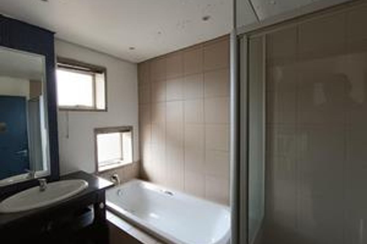A functional bathroom featuring a built-in bathtub, separate glass-enclosed shower, and a vanity basin with a mirror.