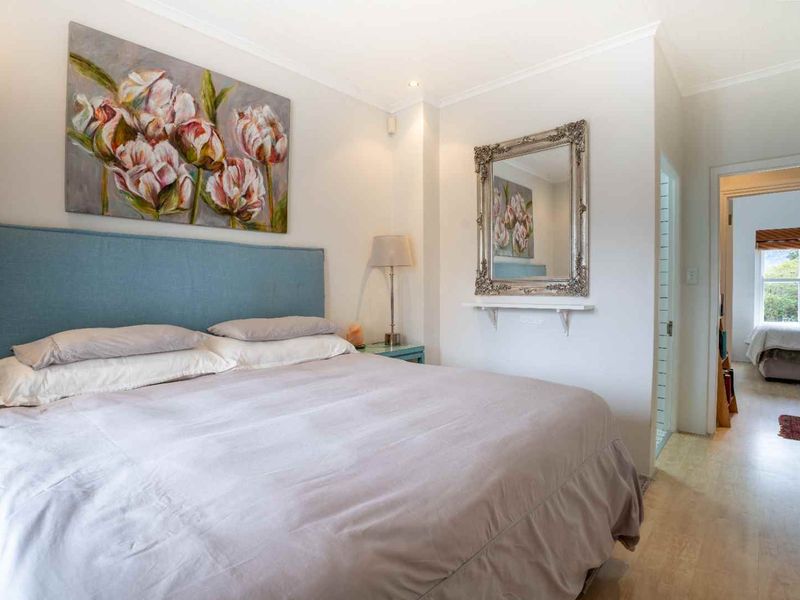 A well-maintained bedroom featuring laminate flooring, recessed lighting, and a neutral color palette, with a view into an adjacent room.