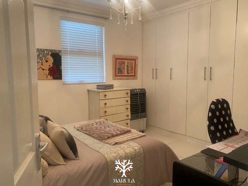 A well-maintained bedroom featuring extensive built-in cupboards, tiled flooring, and classic ceiling cornice detailing.