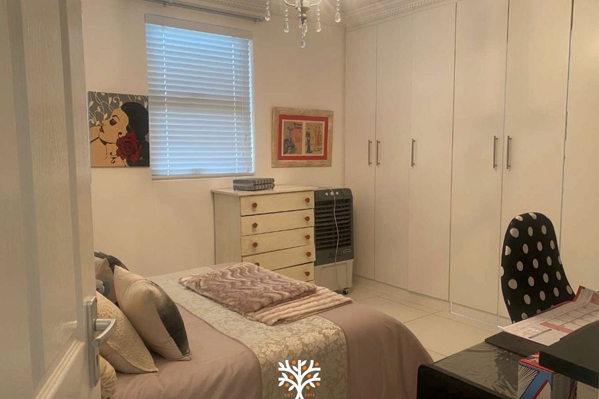 A well-maintained bedroom featuring extensive built-in cupboards, tiled flooring, and classic ceiling cornice detailing.