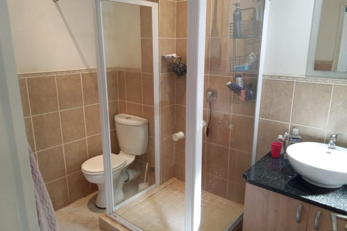A functional bathroom featuring a glass-enclosed shower, a white ceramic toilet, and a vanity unit with a countertop basin.