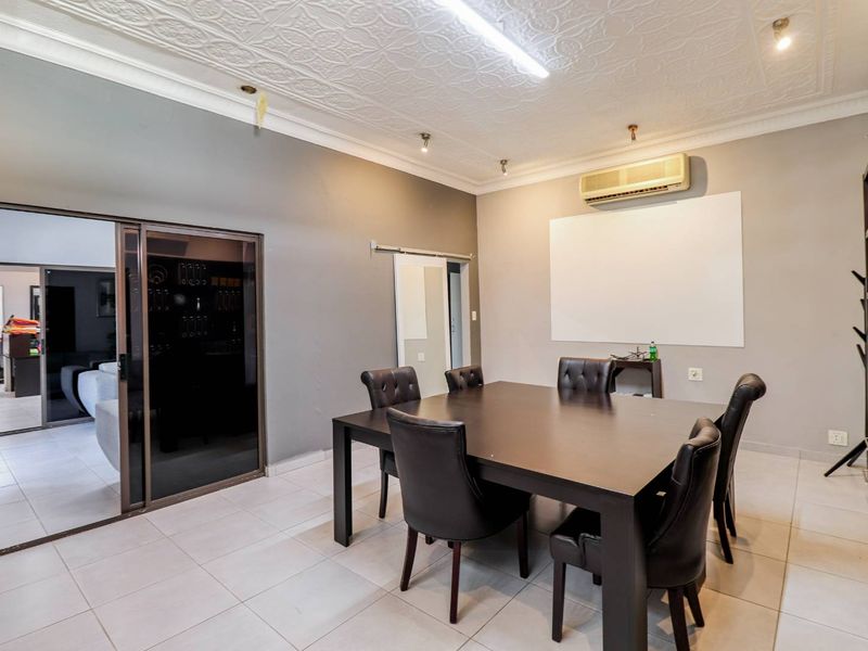 A functional office meeting room featuring tiled flooring, a wall-mounted air conditioning unit, and built-in shelving, with sliding door access to an adjacent space.