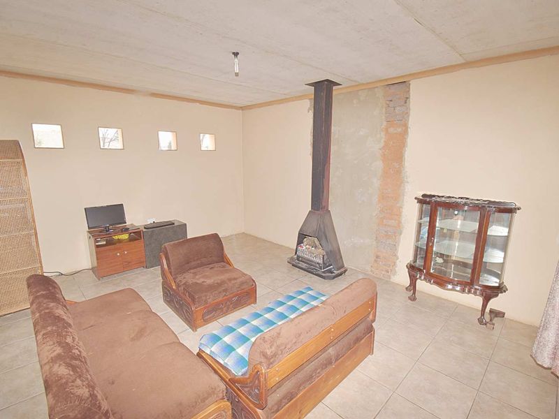 Living room featuring tiled flooring and a central freestanding fireplace with exposed brickwork detail.