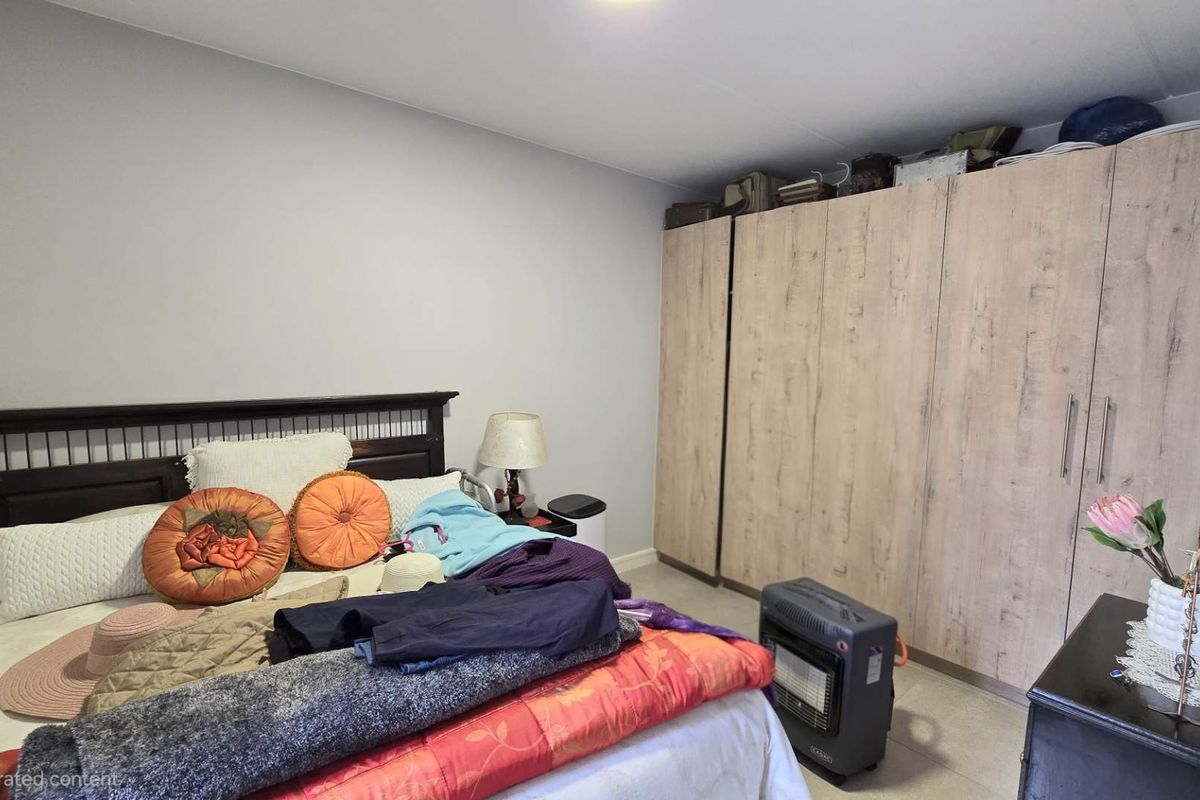 A bedroom featuring built-in wooden wardrobes with a light wood grain finish, providing ample storage space.