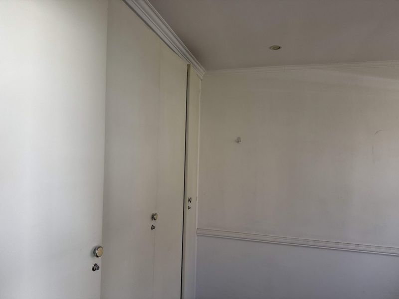 An empty bedroom featuring built-in cupboards, crown molding, and chair rail detailing, providing a neutral canvas for personalization.