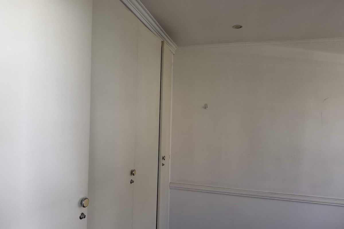 An empty bedroom featuring built-in cupboards, crown molding, and chair rail detailing, providing a neutral canvas for personalization.