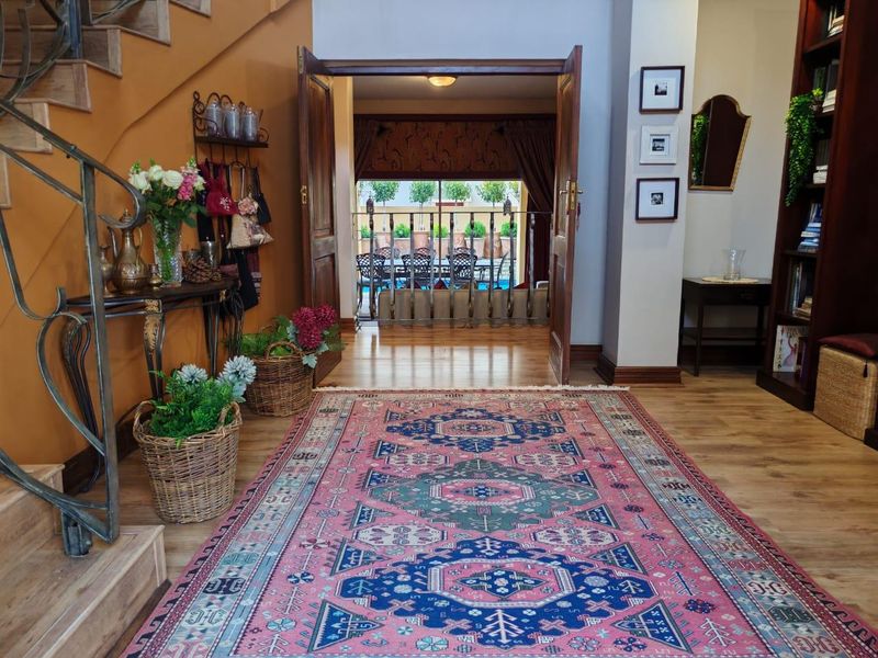 Welcoming entrance hall featuring hardwood flooring, a decorative wrought iron staircase balustrade, and double doors leading to an outdoor patio area.