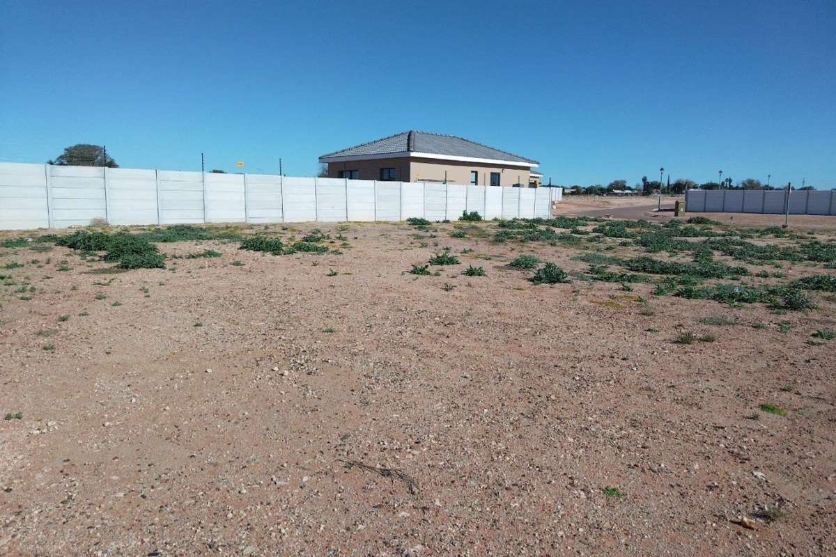 A vacant residential plot featuring a precast concrete boundary wall and installed electric fencing, ready for development.