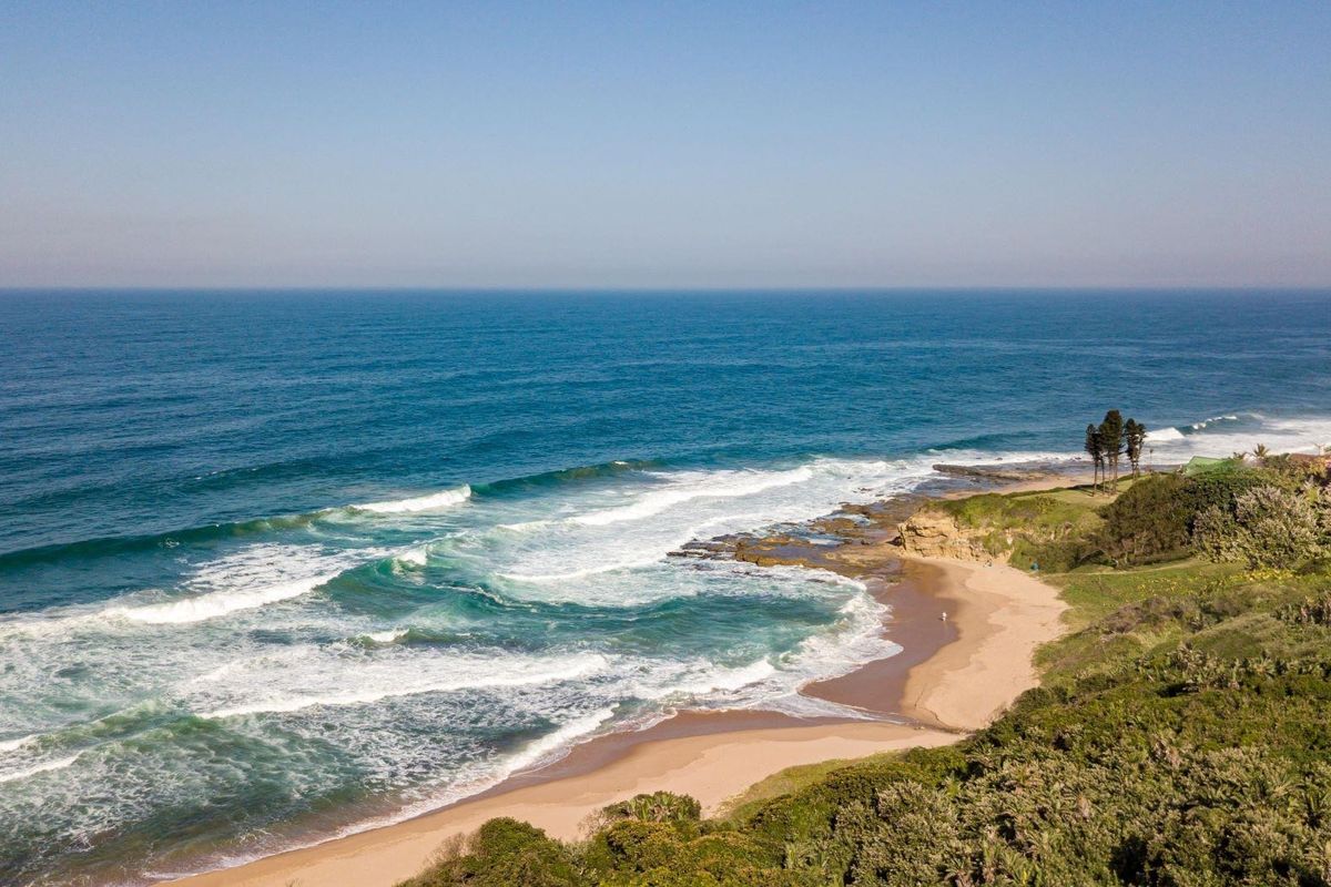 An aerial view of the coastline showcasing the beach, ocean waves, and surrounding natural landscape.