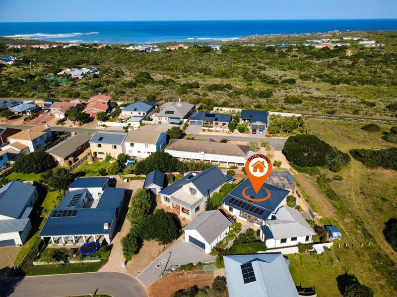 Aerial view of the residential property showing the roof structure, solar panel installation, and surrounding neighborhood layout near the coastline.