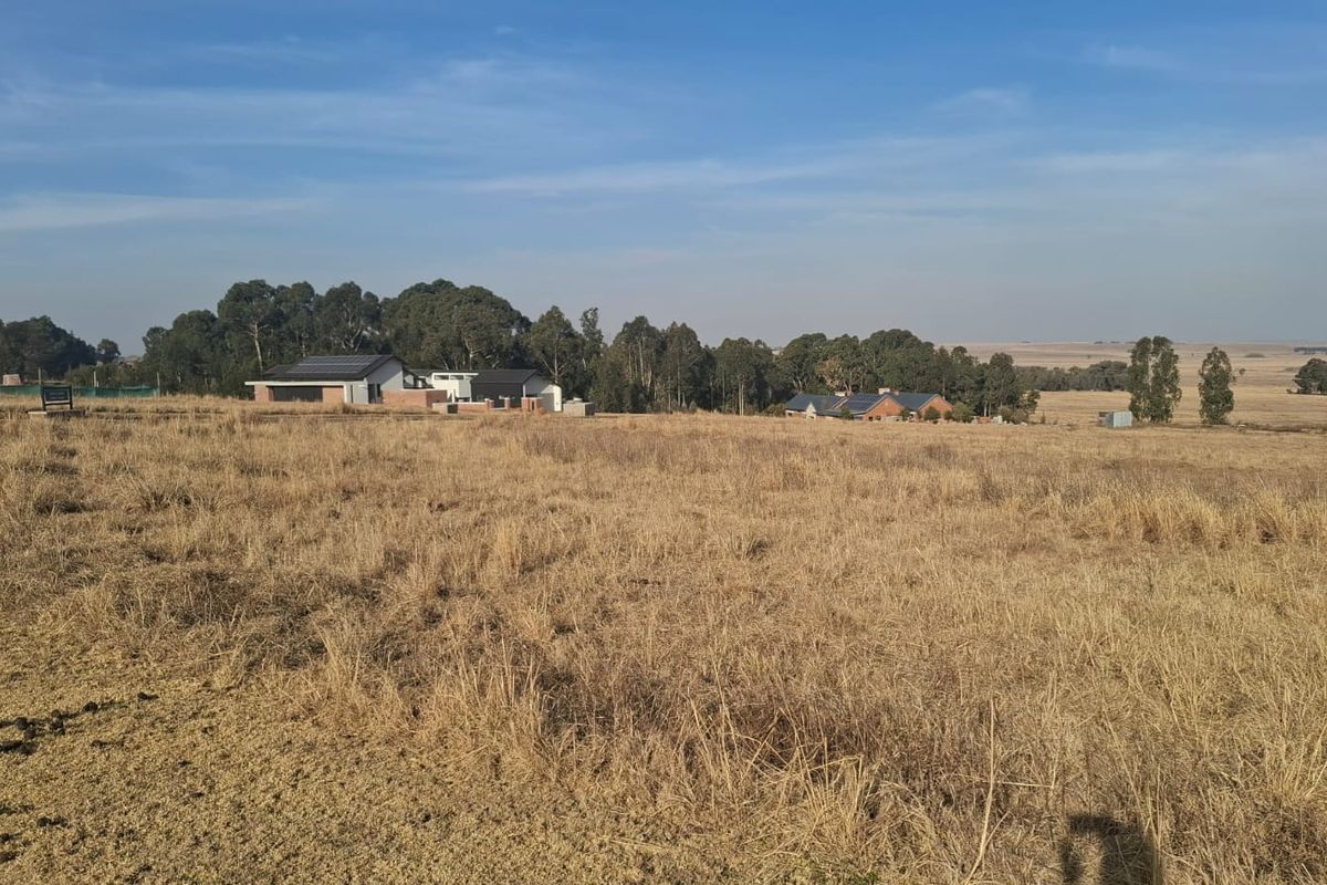 A wide-angle view of the vacant residential land, showcasing the surrounding landscape and nearby established properties.