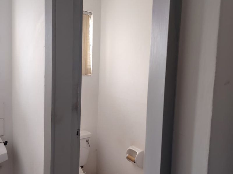 A small, functional bathroom featuring a standard toilet and a window, currently in need of cosmetic updates to improve its overall condition.