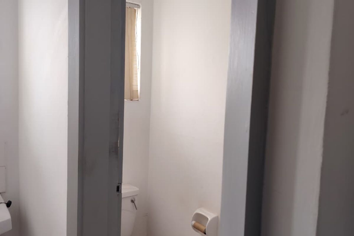 A small, functional bathroom featuring a standard toilet and a window, currently in need of cosmetic updates to improve its overall condition.