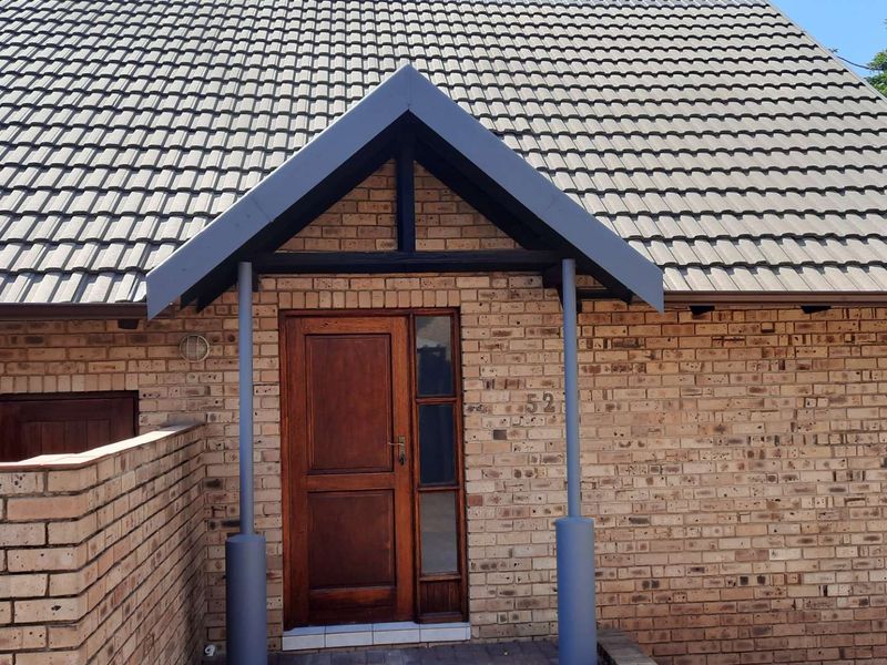 Front entrance of the townhouse featuring a classic brick facade, a covered porch with a pitched roof, and a solid timber front door.