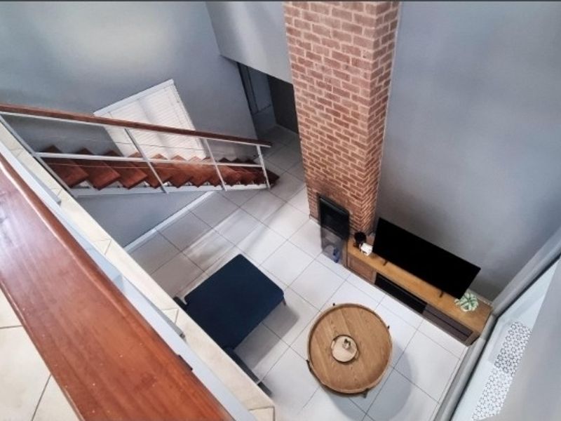 A high-angle view of a living area featuring an exposed brick chimney breast, a built-in fireplace, and a staircase with wooden treads.