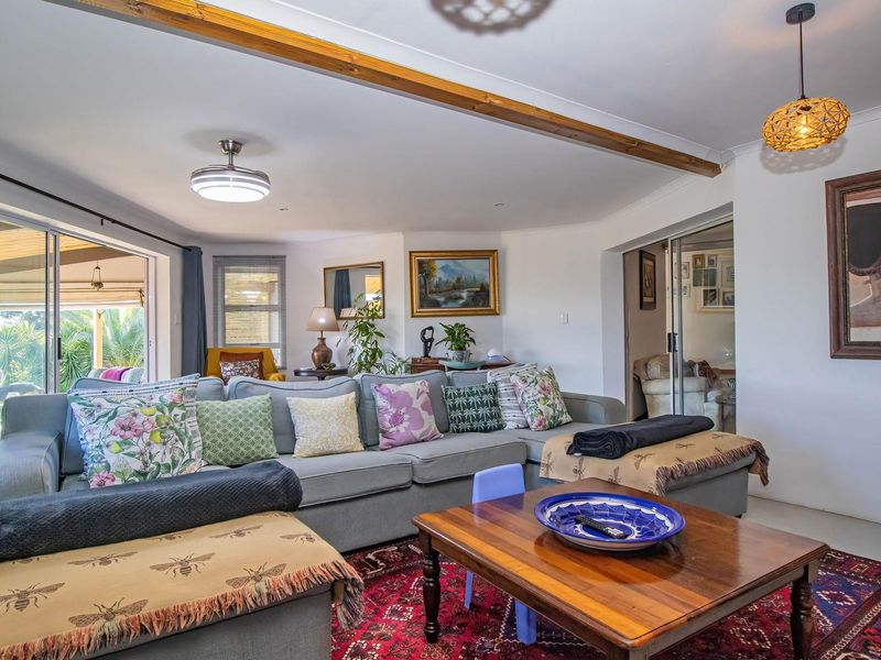 Spacious living room featuring an exposed timber ceiling beam, tiled flooring, and large sliding glass doors providing seamless access to the outdoor patio area.