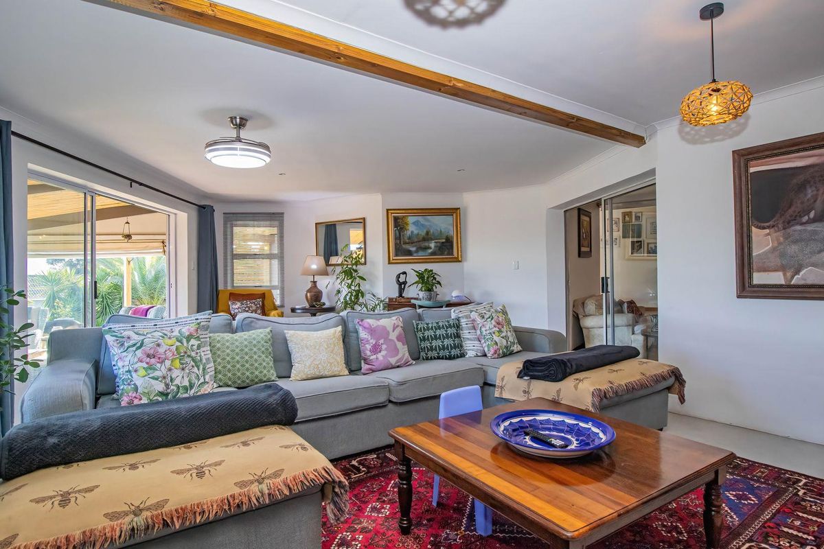 Spacious living room featuring an exposed timber ceiling beam, tiled flooring, and large sliding glass doors providing seamless access to the outdoor patio area.
