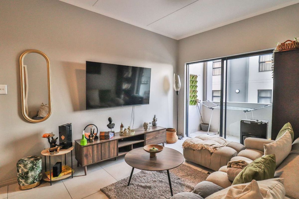 A comfortable living room featuring large sliding glass doors that open onto a private balcony, providing natural light and seamless indoor-outdoor flow.