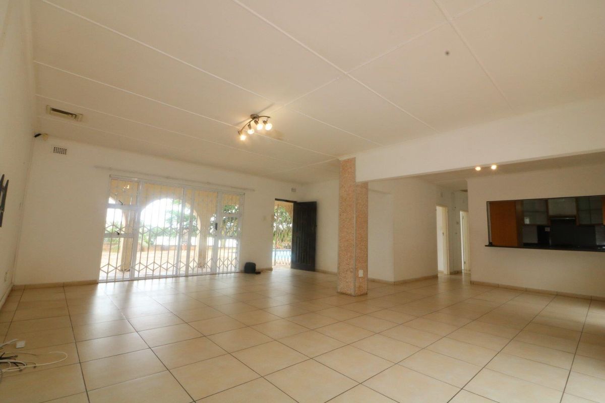 Spacious open-plan living area featuring ceramic floor tiles, a structural support column, and sliding glass doors leading to an outdoor space.