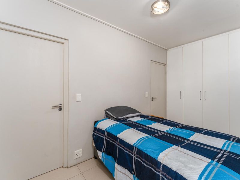 A functional bedroom featuring neutral walls, tiled flooring, and ample built-in cupboard storage space.