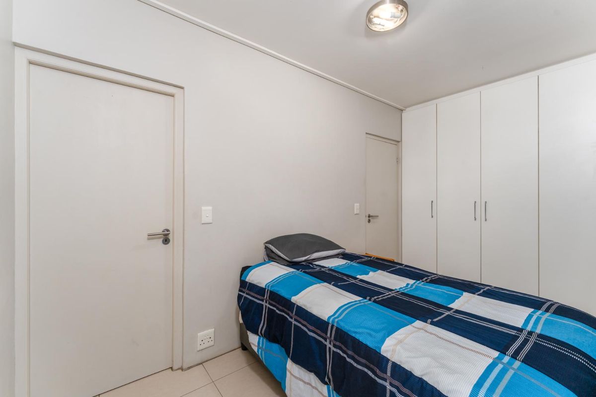 A functional bedroom featuring neutral walls, tiled flooring, and ample built-in cupboard storage space.