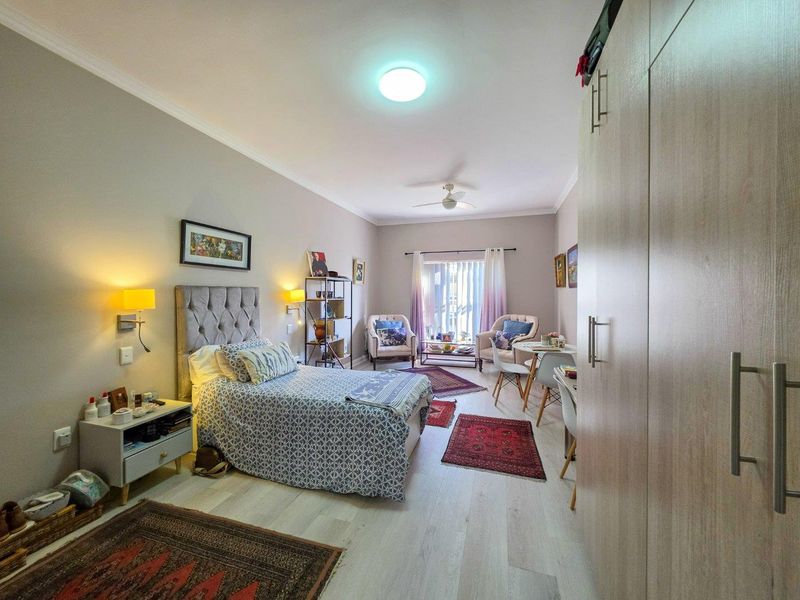 A well-maintained bedroom featuring light-toned laminate flooring, a built-in wardrobe, and a ceiling fan, offering a comfortable and functional living space.