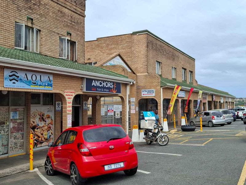 Front exterior view of a commercial strip mall featuring brick facade, storefronts, and dedicated customer parking area.