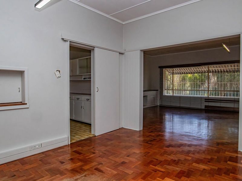 An open-plan living area featuring original parquet flooring, a built-in wall niche, and a sliding door leading to a secondary space.