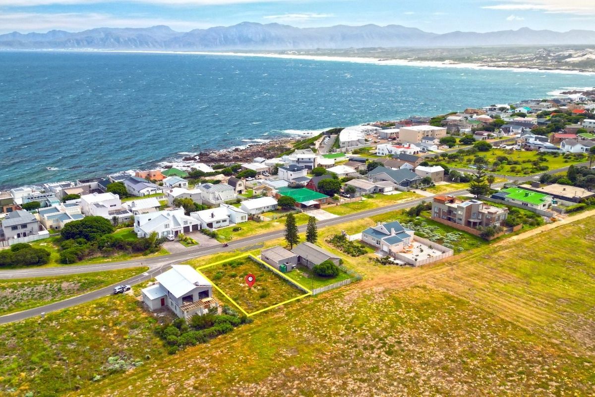 Aerial view of a vacant residential plot situated in a coastal neighborhood with scenic ocean and mountain views.