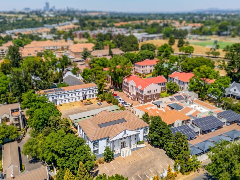 Aerial view of the office complex featuring multiple buildings, solar panel installations, and paved parking facilities within a landscaped estate setting.