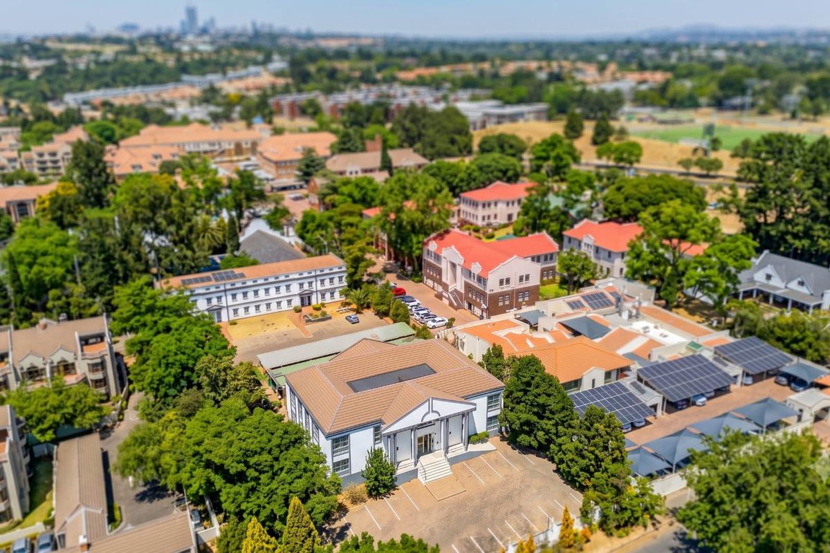 Aerial view of the office complex featuring multiple buildings, solar panel installations, and paved parking facilities within a landscaped estate setting.