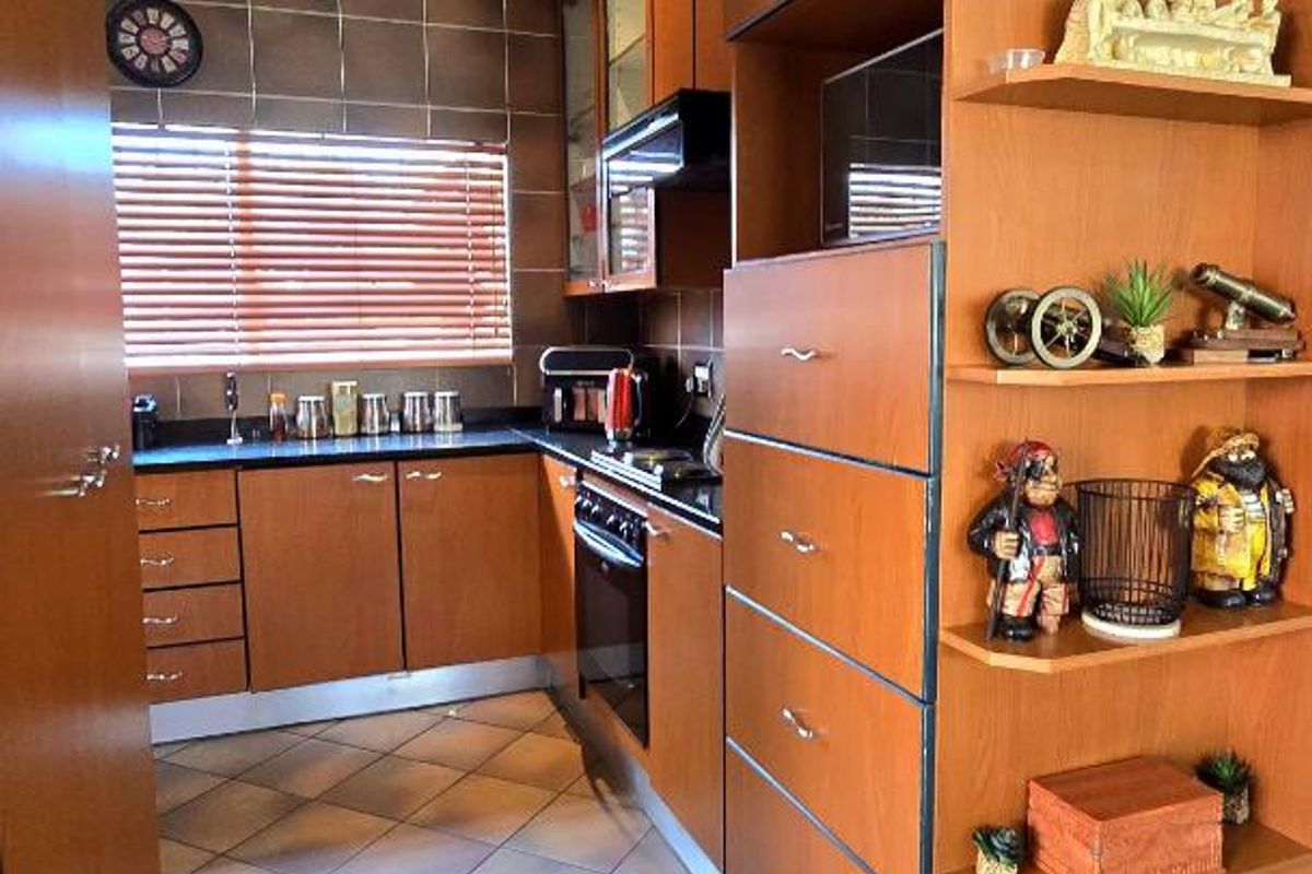 A functional kitchen featuring wood-finish cabinetry, built-in oven and hob, tiled backsplash, and durable floor tiles.