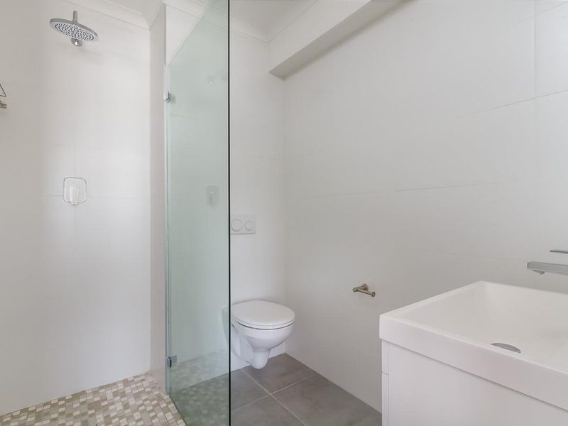 Modern bathroom featuring a walk-in shower with a glass screen, wall-mounted toilet, and a sleek vanity basin with chrome fixtures.