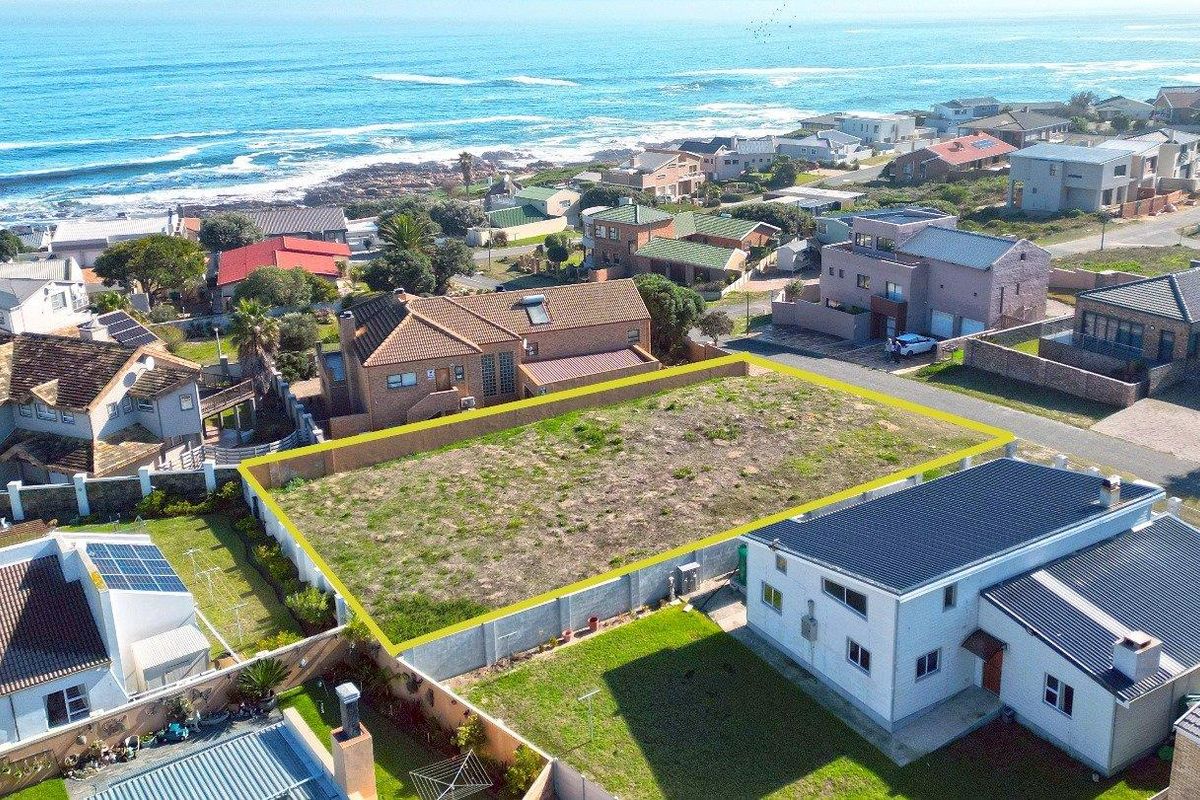 Aerial view of a vacant residential plot in a coastal neighborhood, featuring perimeter boundary walls and proximity to the ocean.