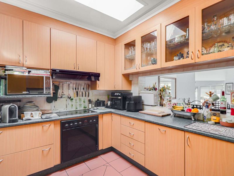 A functional kitchen featuring light wood-tone cabinetry, laminate countertops, a built-in oven, and a skylight providing natural overhead lighting.