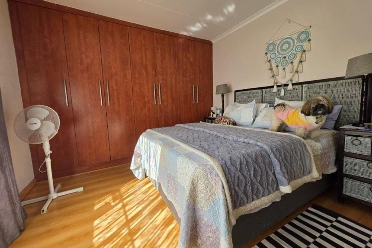 A bedroom featuring laminate flooring and extensive floor-to-ceiling built-in wooden cupboards.
