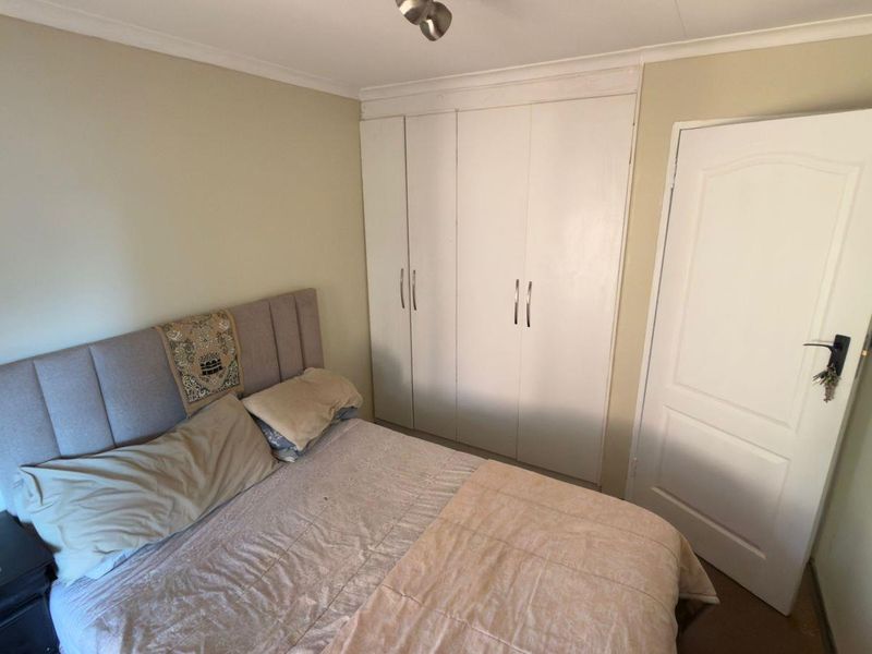A functional bedroom featuring built-in cupboards and a standard panel door, providing essential storage and access.
