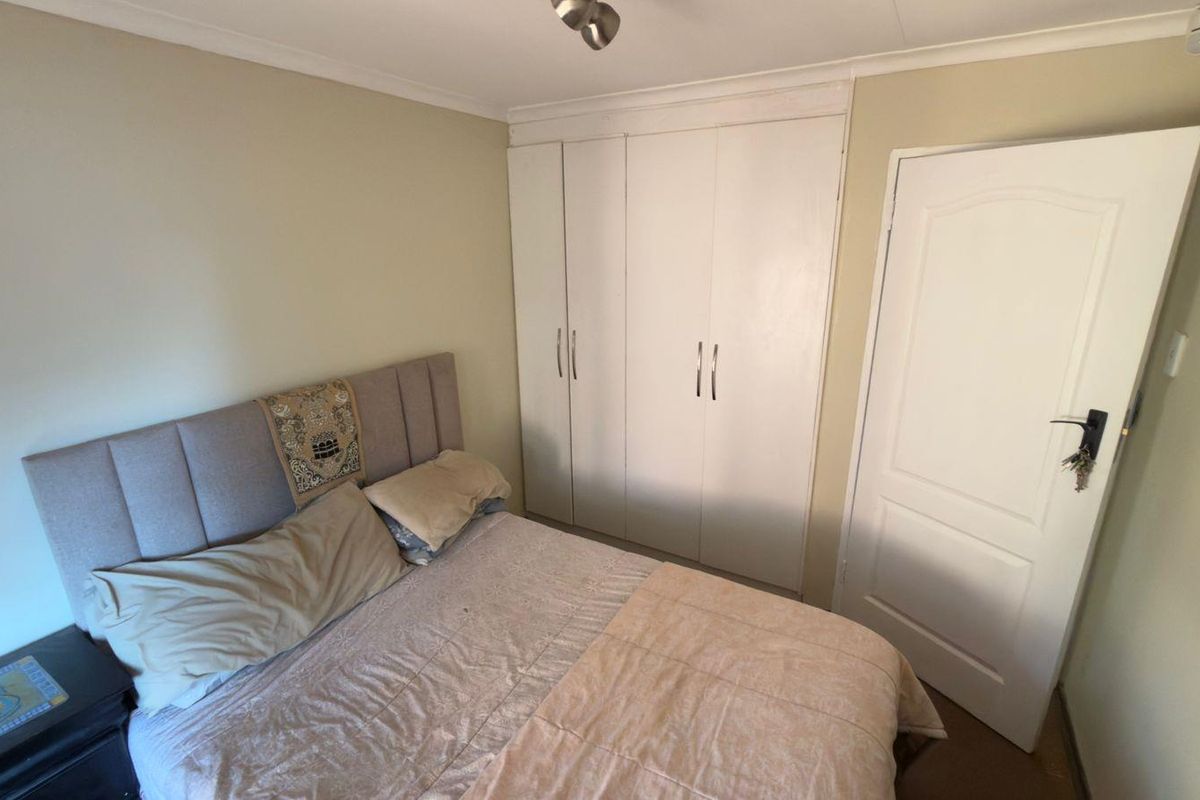 A functional bedroom featuring built-in cupboards and a standard panel door, providing essential storage and access.